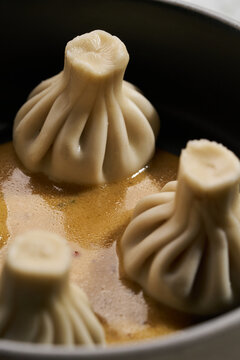Georgian khinkali dumplings served with sauce in ceramic bowl