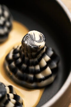 Striped khinkali dumplings with sauce in ceramic bowl
