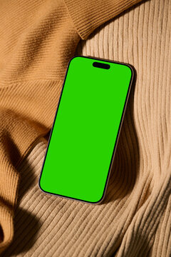 Smartphone with green screen on a brown sweater