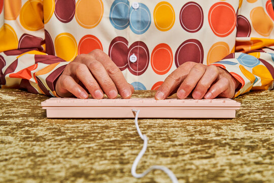 a man types on a pink keyboard on a gold table