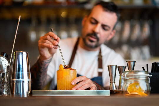 Bartender crafting cocktail with garnish at bar