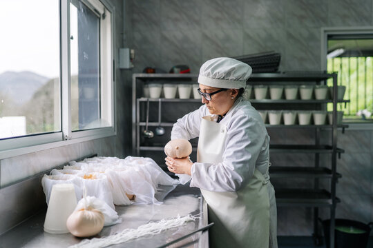 Artisan cheesemaker crafting fresh cheese in dairy factory