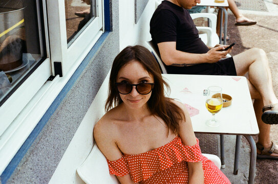 Woman in Red Polka Dot Dress Sitting at Outdoor Cafe Table