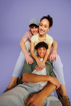 Diverse friends stack together laughing on purple background