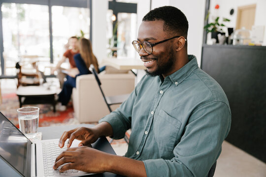 Lifestyle portrait of young black man working on laptop in cafe 
