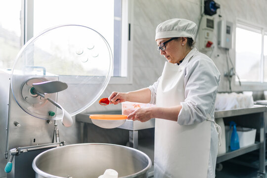 Artisan cheesemaker adding paprika to cheese production