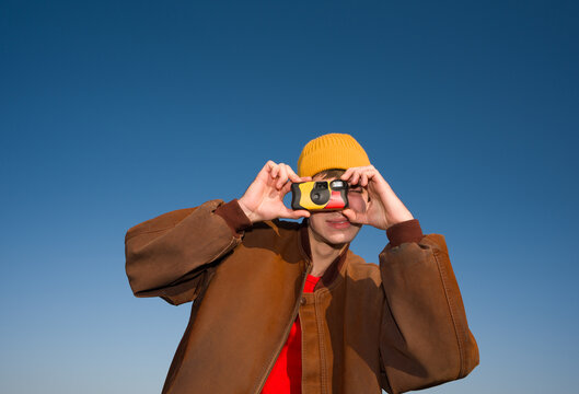 Man Using Disposable Camera Against Blue Sky 