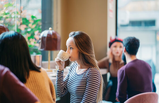 Young woman enjoying coffee with friends at cafe