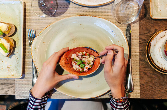 Person enjoying ceviche appetizer at fine dining restaurant