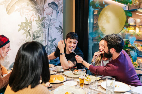Friends sharing food and enjoying dinner at restaurant