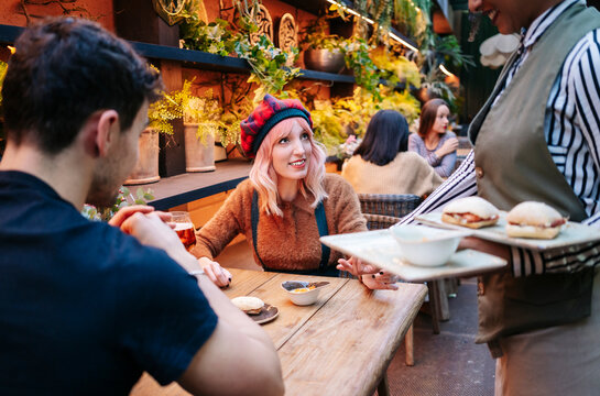 Young couple enjoying food and drinks at restaurant bar