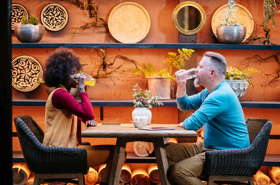 Diverse couple drinking beverages at restaurant bar