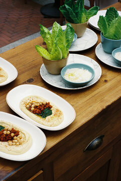 Film Photo of Hummus Plates with Lettuce and Dips on Restaurant Table