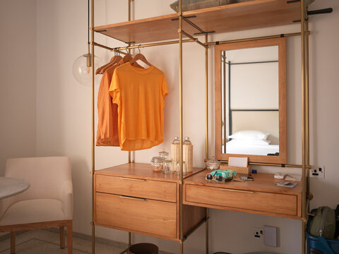 Bright Clothing Hangs in a Simple Room With a Mirror and Desk