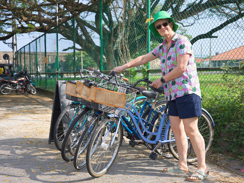 Senior Woman on Vacation Hiring Bicycle at Galle Fort