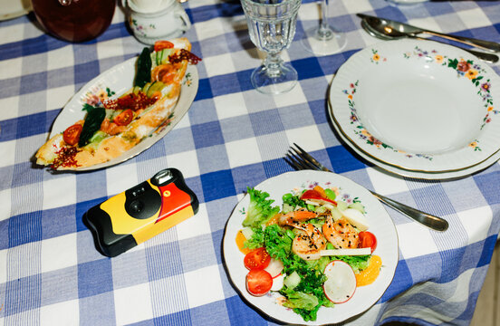 Dining Table Setup With Salad and Main Dish on Checkered Tablecloth