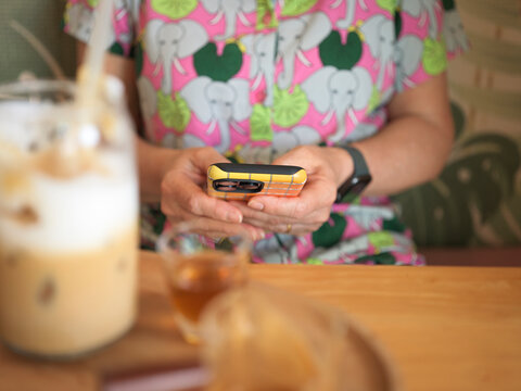 Woman Checks Mobile Phone While Sitting at a Cafe Table