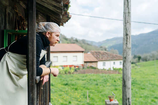 Artisan cheesemaker contemplating rural village landscape