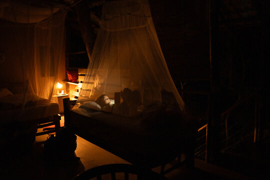 Child Reading Under a Mosquito Net at night
