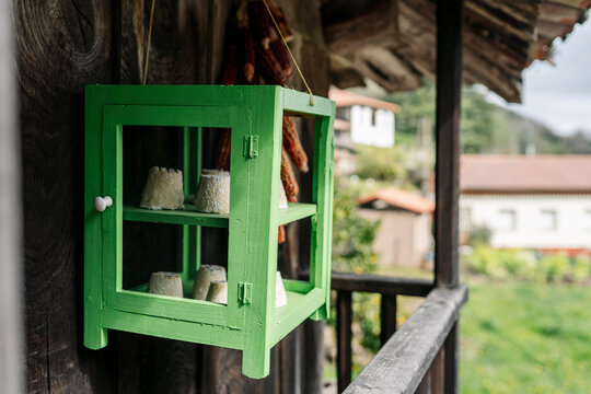 Artisan cheese aging inside green wooden cabinet in rural setting
