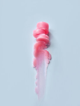 Pink lip balm smear on a light blue background