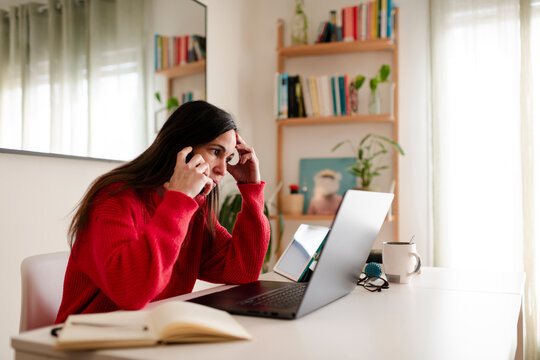 Stressed Woman on Phone Call Staring at Laptop