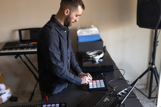Dj using pad controller with colorful lights in home studio