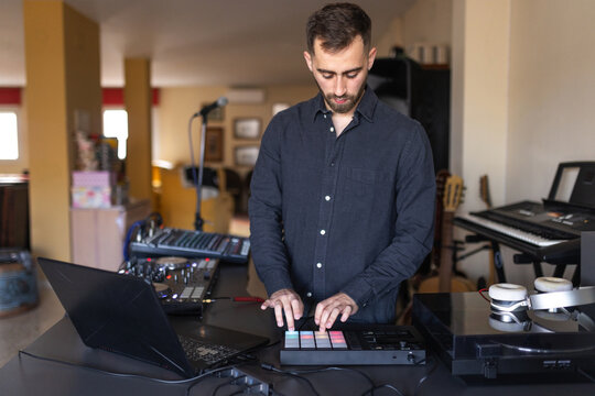 Dj using pad controller with colorful lights in home studio