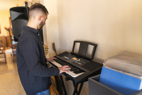 Man playing piano standing in home studio