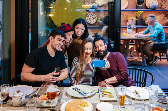 Friends taking selfie enjoying dinner at restaurant