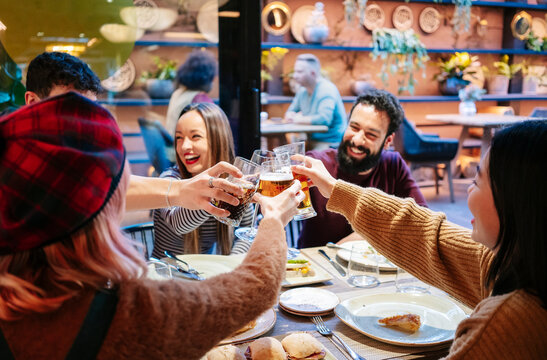 Friends toasting drinks celebrating dinner at restaurant