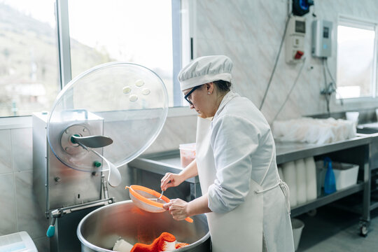 Artisan cheesemaker adding spices to fresh cheese