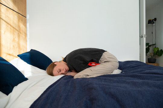 Person experiencing abdominal discomfort using a heating pad