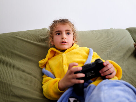 Child playing video game at home holding controller