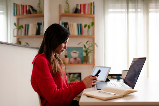 Calm Woman Checking Smartphone at Multi-Device Desk