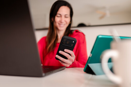 Joyful Woman Holding modern phone at Multi-Device Desk