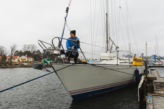 Female Sailor Crouching at the Bow While Moored at Pier