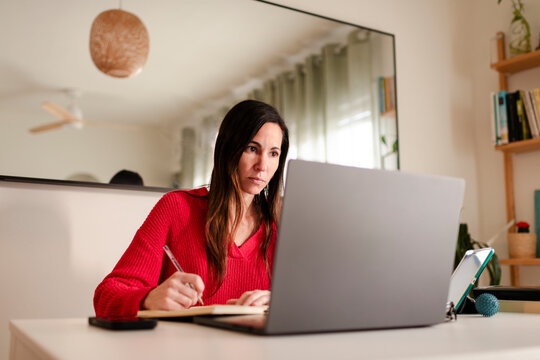 Determined Woman Taking Notes While Studying Online