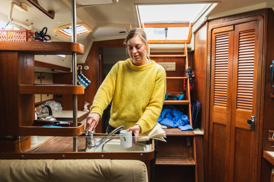 Woman Sailor Filling Water Mug at Sailing Boat Galley Sink