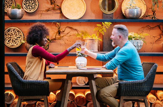 Diverse couple toasting drinks enjoying happy bar restaurant date