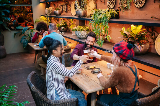 Friends toasting beer glasses at cafe bar