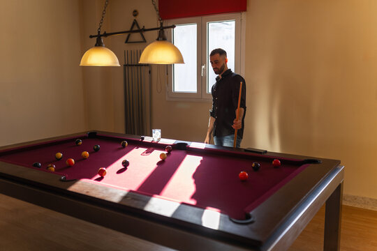Man standing and observing billiard table at home