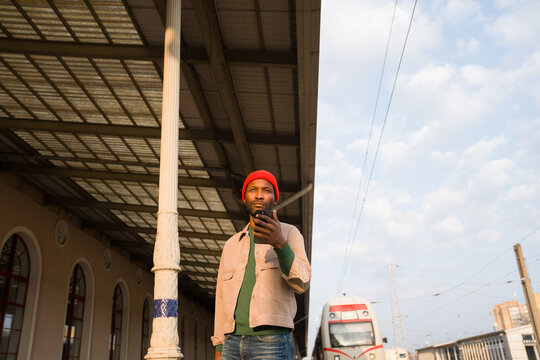 Man Standing at Train Station With Phone in Hand