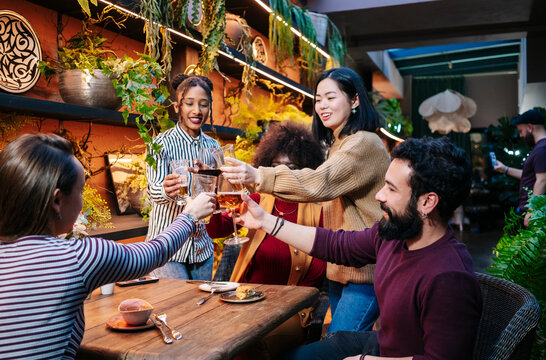 Friends toasting drinks at festive bar restaurant