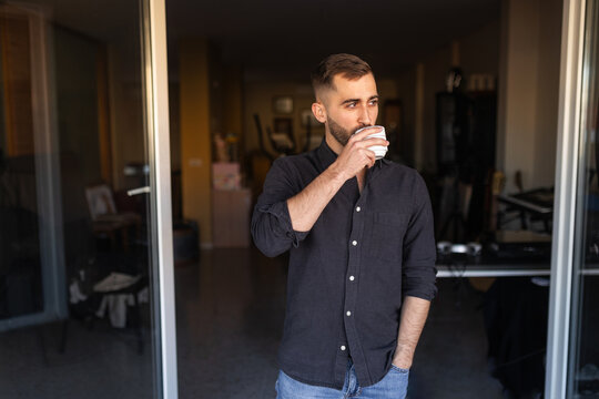 Bearded man drinking coffee at home