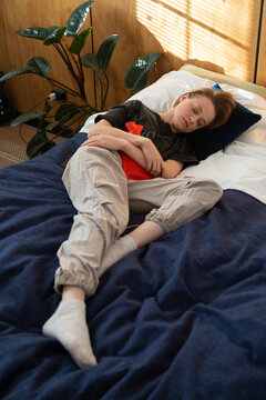 Person finding period pain relief using hot water bottle