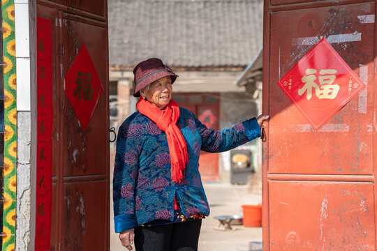 Elderly woman opening traditional red doors
