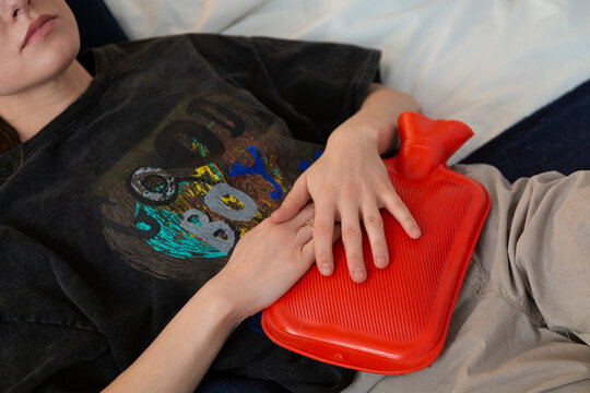 Person experiencing period pain holding hot water bottle