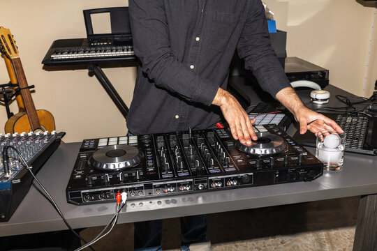 DJ mixing music while holding a drink in his studio