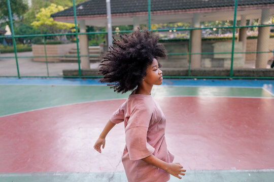Active girl on basketball court, hair in motion.